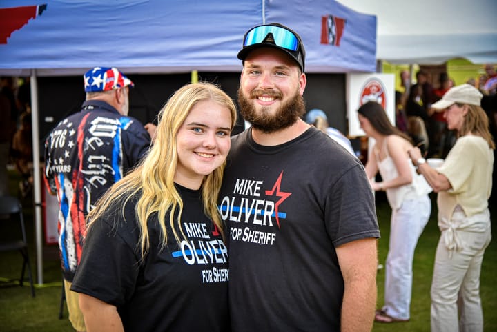 Two guests in matching shirts posing near the tent