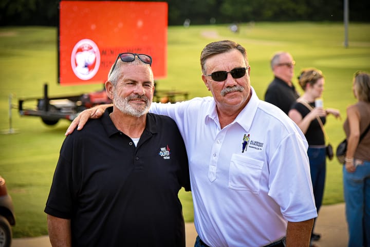 Two guests standing together near the event sign