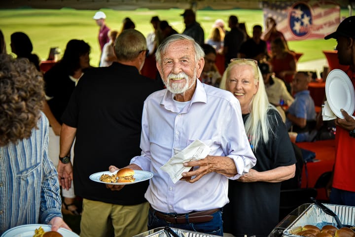 A guest carrying a plate of food beneath the tent